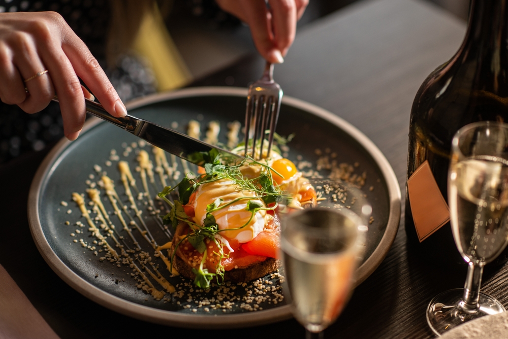 Woman,Eating,Fresh,Toast,With,Salmon,,Poached,Eggs,,Salad,And